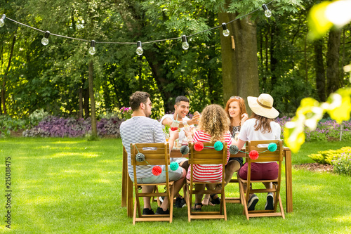 Group of smiling friends enjoying outdoor birthday party during summer