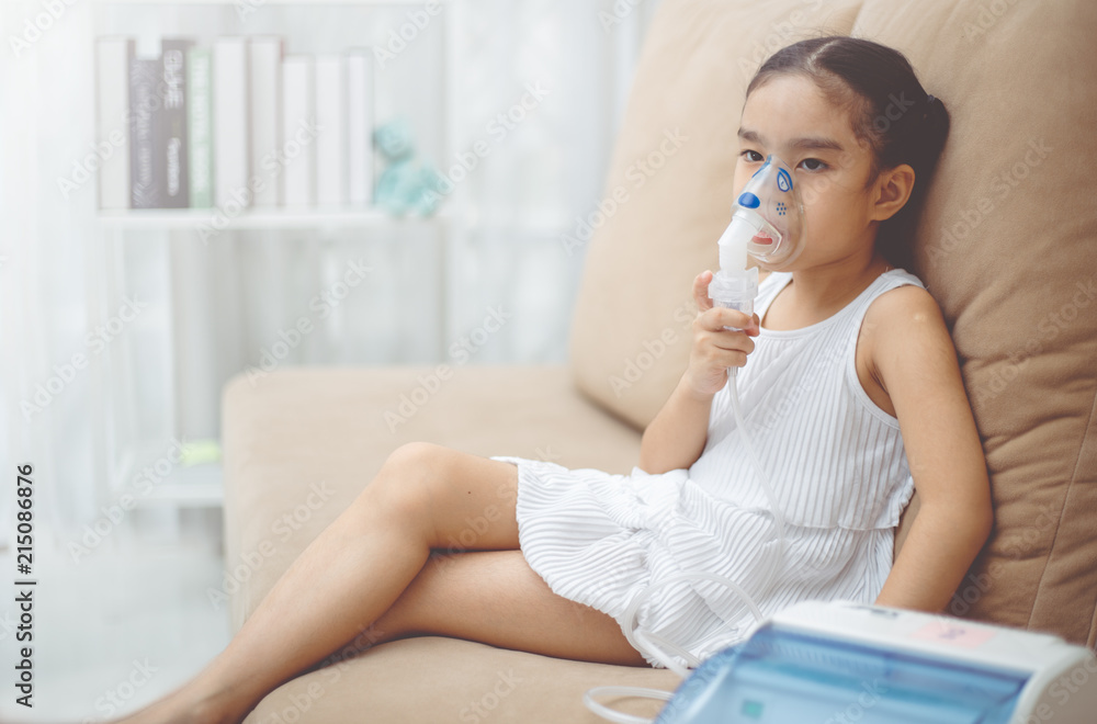 Cute Asian child patient inhalation therapy by the mask of inhaler with soft stream smoke from bronchodilator. Cute Asian child patient inhalation therapy by the mask of inhaler with soft stream smoke from bronchodilator.