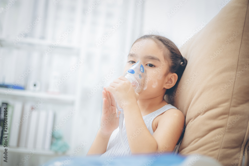 Cute Asian child patient inhalation therapy by the mask of inhaler with soft stream smoke from bronchodilator. Cute Asian child patient inhalation therapy by the mask of inhaler with soft stream smoke from bronchodilator.