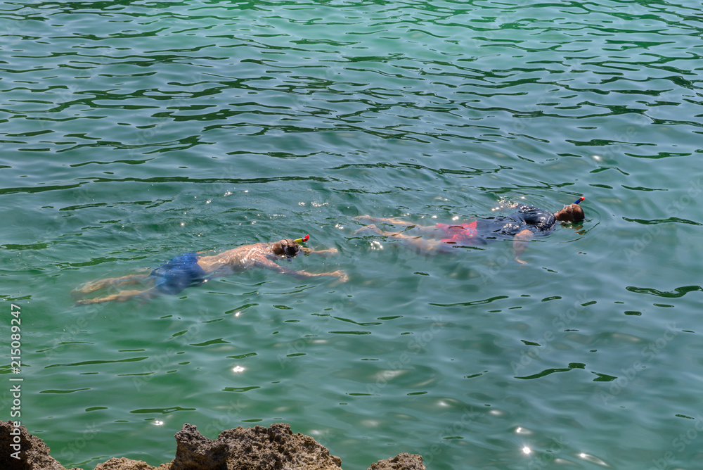 man in a scuba mask swims in blue sea water