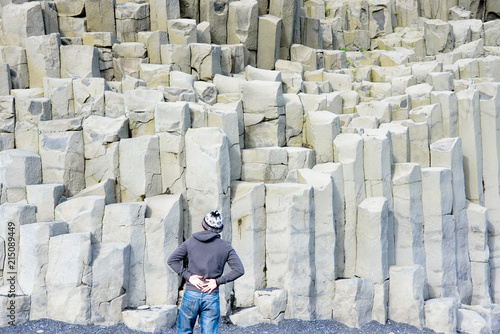 Montaña Reynisfjall con columna de basalto en Reynisfjara (Reynisfjoru) en la costa sur de Islandia con persona de espaldas photo