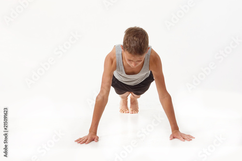 Teen in a T-shirt and shorts performs gymnastic exercises.