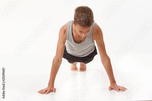 Teen in a T-shirt and shorts performs gymnastic exercises. © makam1969