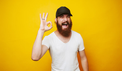 Young cheerful bearded man showing OK sign gesture