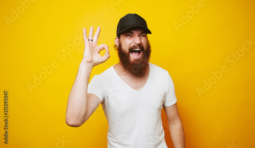 Young cheerful bearded man showing OK sign gesture photo