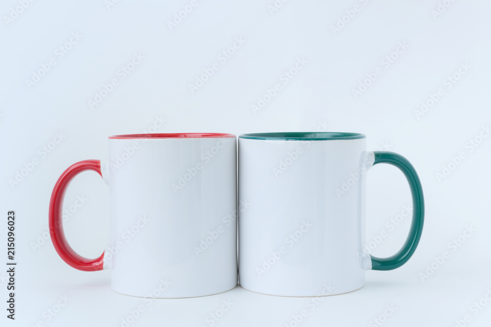 Two white mugs, with a green and red handle on a light background. Two white mugs, with a green and red handle on a light background.