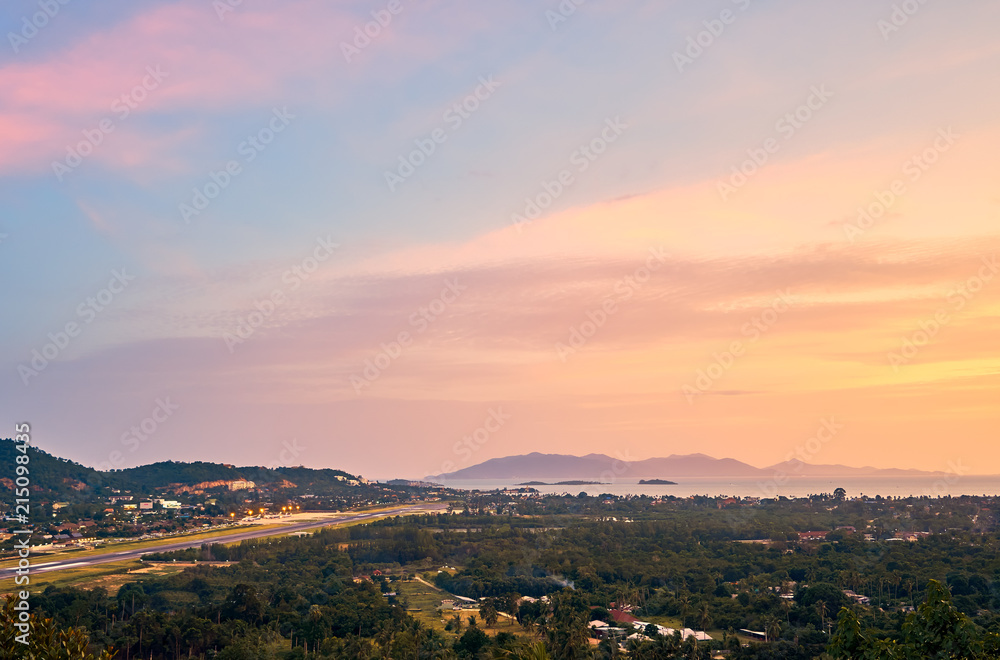 Colourful sunset over airport, mountains and forest on a tropical island      