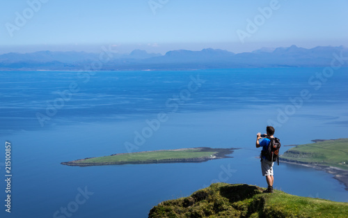 Man Taking Picture at Cliff on Quiraing Trail in Summer Skye Scotland UK