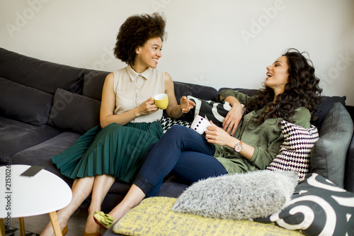 Two multiracial young women chatting and drinking coffe photo