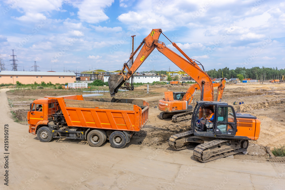 Two excavators load the earth into a dump truck Two excavators load the earth into a dump truck