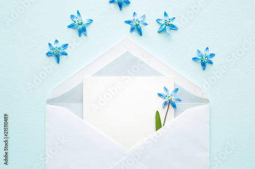 Opened white envelope with fresh, beautiful blue snowdrops ( scilla ) on light pastel background. Sending or receiving messages or greetings. Empty place for inspirational, motivational text or quote. photo