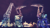 Illuminated old port cranes on a boulevard in Szczecin City at night, color toning applied, Poland.