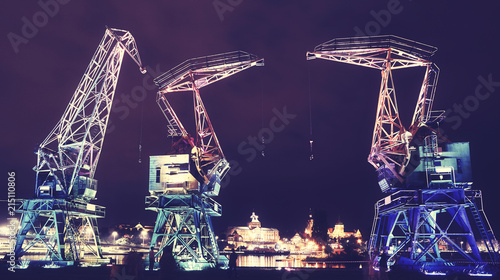 Illuminated old port cranes on a boulevard in Szczecin City at night, color toning applied, Poland.