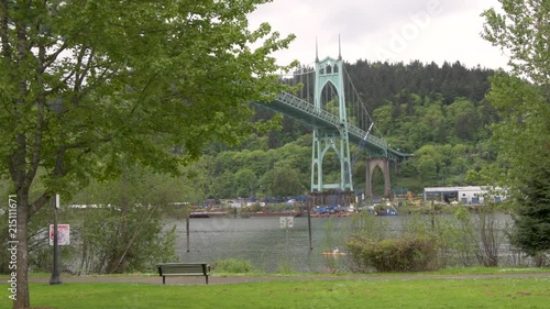 Cathedral Park in Portland, Oregon on an overcast dayView of the St Johns Bridge crossing the Willamette river, framed by trees, from . A kayaker goes by. photo