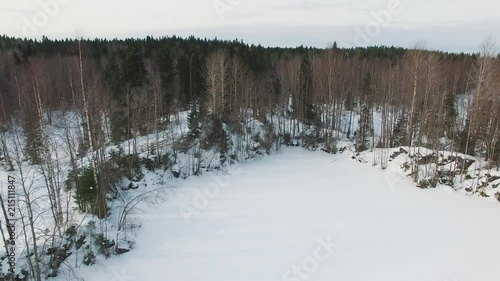 Wallpaper Mural Flying low over snow-covered frozen lake towards winter forest with spruces, firs and trees without leaves at bright day. Russia, Karelia. Torontodigital.ca