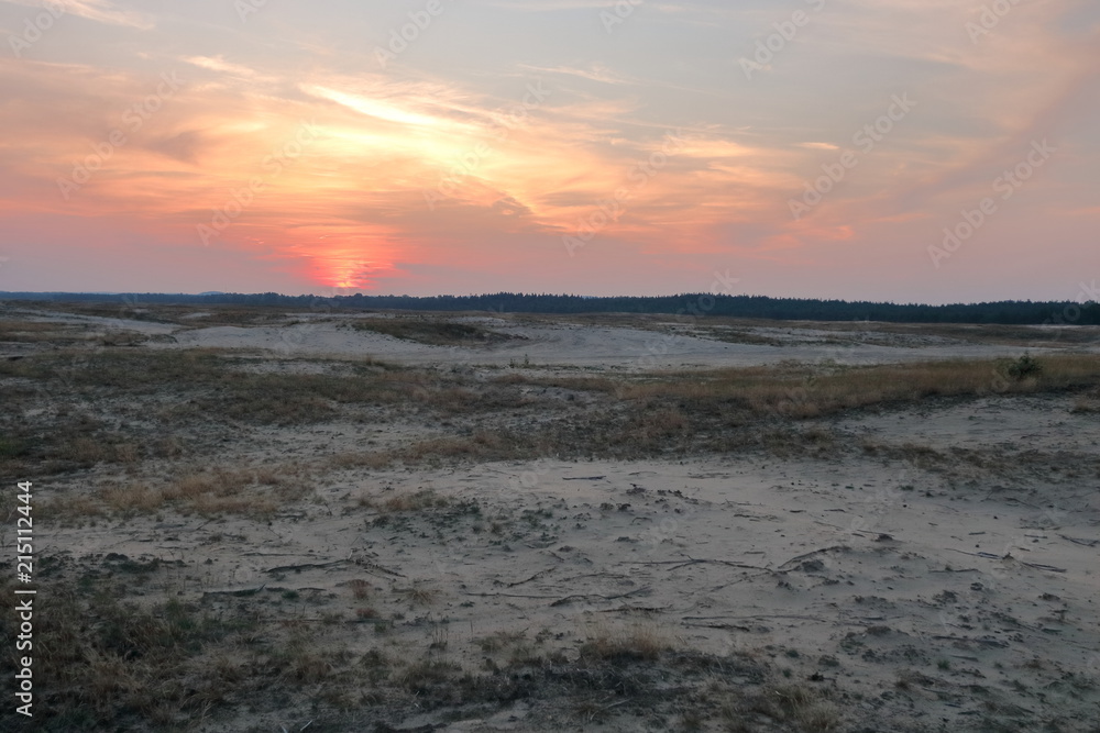 Zachód słońca nad pustynnym, suchym terenem, pusto, nikogo, niebo w ognistych barwach Zachód słońca nad pustynnym, suchym terenem, pusto, nikogo, niebo w ognistych barwach