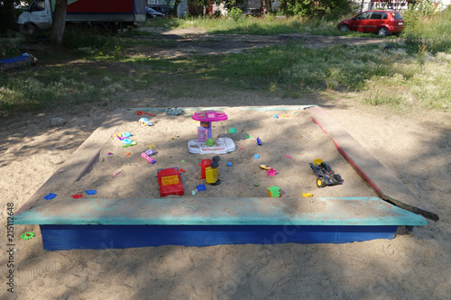 Sandbox with scattered children's toys in the courtyard of the house on the playground