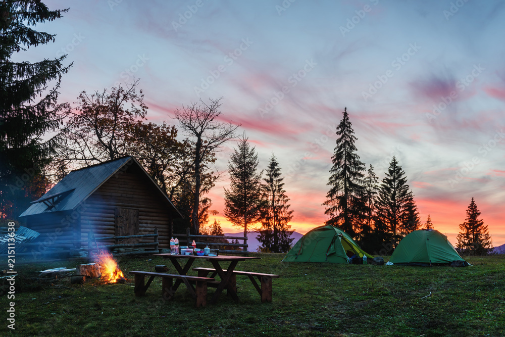 Three tents lighted from the inside by a flashlight against the backdrop of an incredible sunset sky. Amazing evening landscape. Tourism concept