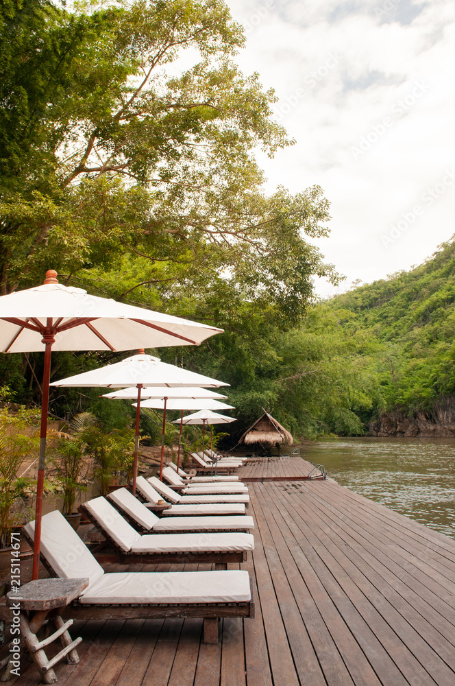 Resort style beach daybeds and umbrellas by river Kwai, Kanchanaburi, Thailand