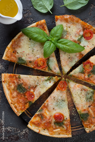 Close-up of sliced pizza with cheese and cherry tomatoes, view from above, vertical shot