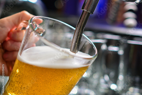 close-up of barman hand at beer tap pouring a draught lager beer