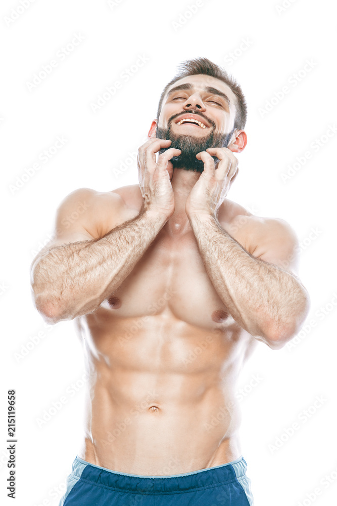 Fototapeta premium He stroked and touched his beard. A beautiful beard. Beautiful sporty guy male power. Fitness muscled in blue shorts. on isolated white background.