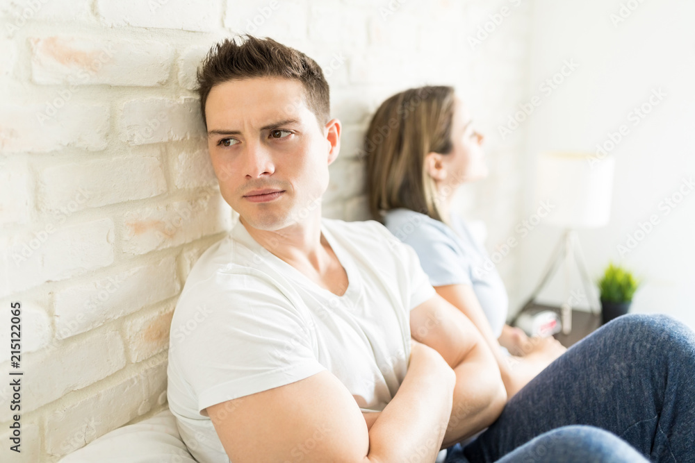 Angry Man Looking Away While Sitting By Girlfriend On Bed Angry Man Looking Away While Sitting By Girlfriend On Bed