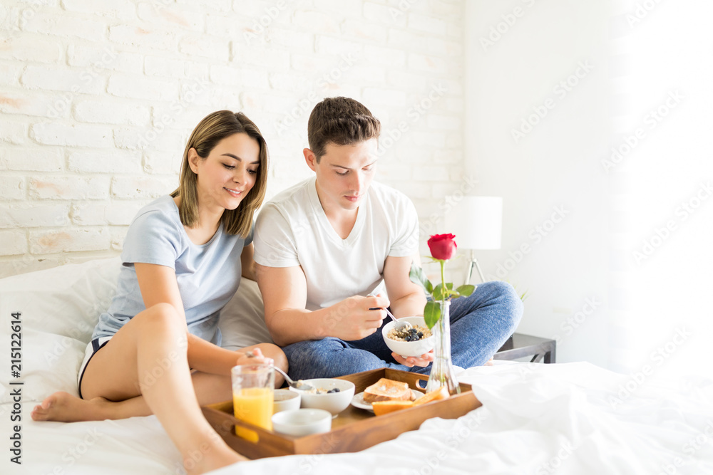 Man And Woman Eating Healthy Breakfast On Bed
