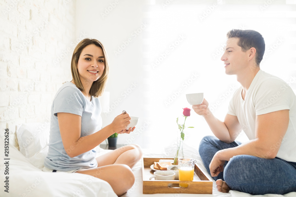 Woman Smiling While Having Breakfast With Boyfriend On Bed Woman Smiling While Having Breakfast With Boyfriend On Bed