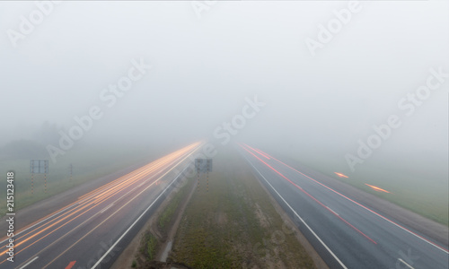 Freeway and tracks of car lights in fog at early morning