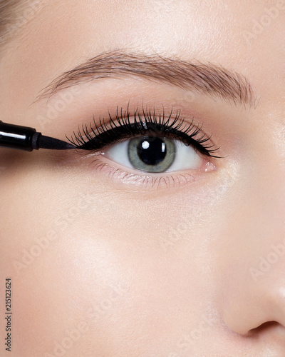 Beautiful woman with bright make up eye with sexy black liner makeup. Fashion arrow shape. Chic evening make-up. Makeup beauty with brush eye liner on pretty woman face