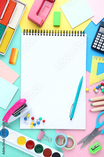 School supplies with blank sheet of paper on colorful background