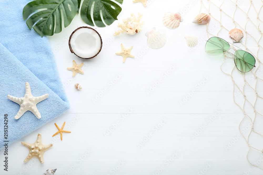 Different seashells with sunglasses and towel on wooden table