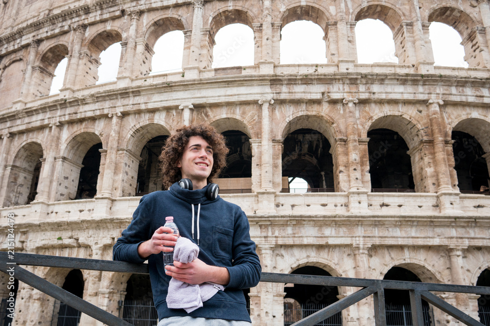 Handsome young guy relaxing after training in front of Colosseum in Rome