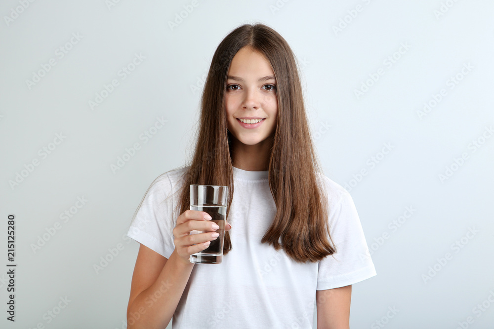 Beautiful young girl with glass of water on grey background Beautiful young girl with glass of water on grey background