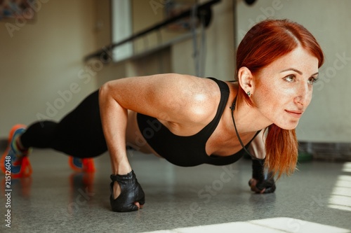 sportive young woman doing push ups in gym