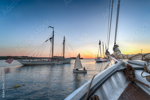 Sailboat Dingy Sails Between Wooden Boats at Sunset