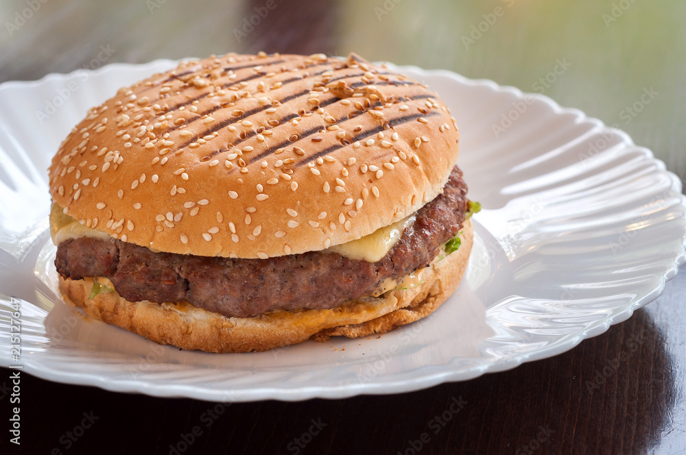 Juicy cheeseburger with cheese on a white plate Juicy cheeseburger with cheese on a white plate
