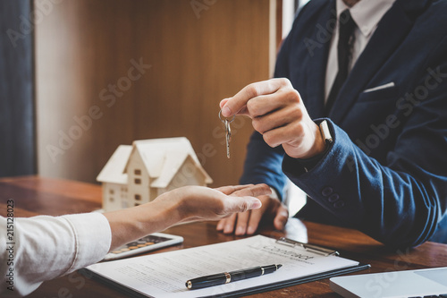Real estate agent Sales manager holding filing keys to customer after signing rental lease contract of sale purchase agreement, concerning mortgage loan offer for and house insurance photo