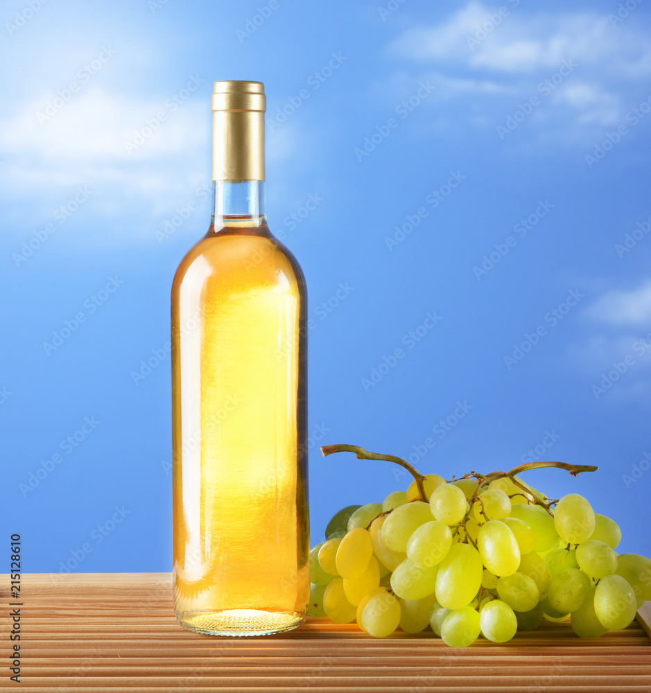 bottle of wine with bunch of grapes - blue sky background bottle of wine with bunch of grapes - blue sky background