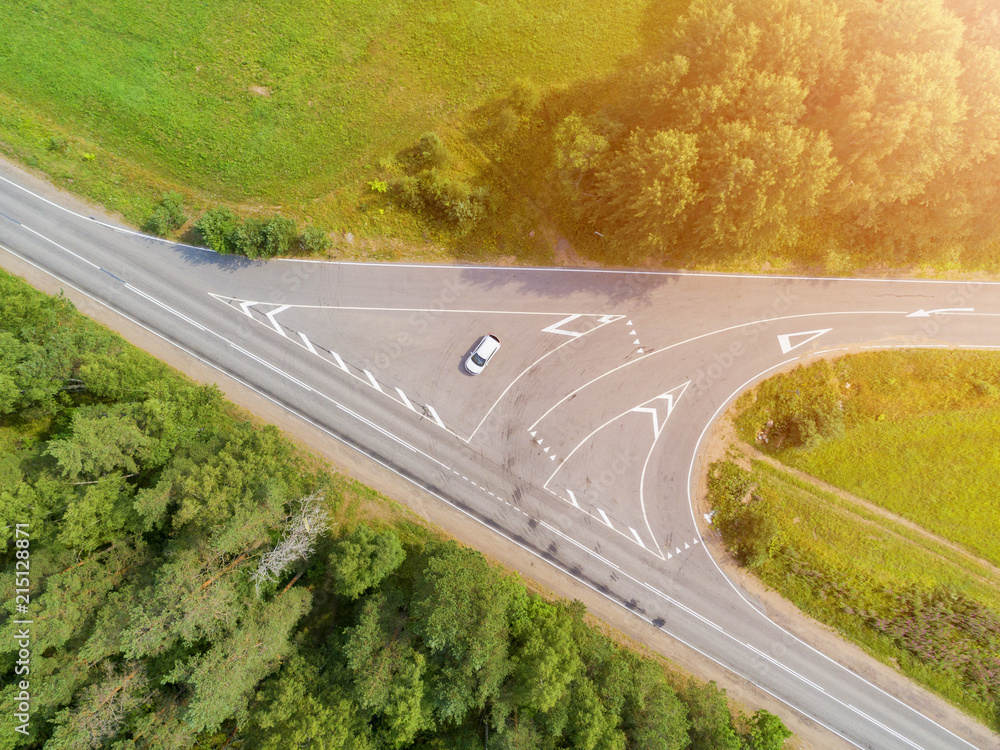 Aerial view of highway with car. Aerial view of a country road with moving car. Car passing by. Aerial road. Aerial view flying. Captured from above with a drone. Soft lighting