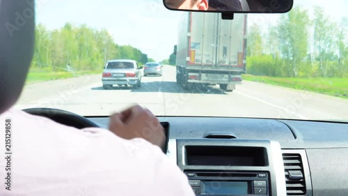 Cars overtake a truck on the road passing through the forest.