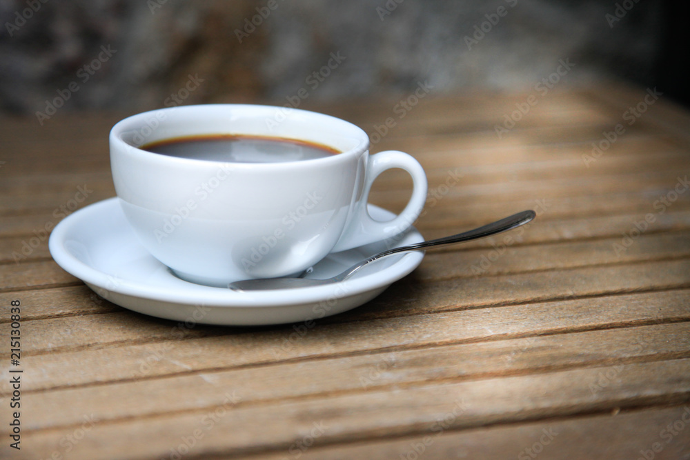White cup with brown coffee on a wooden table. White cup with brown coffee on a wooden table.
