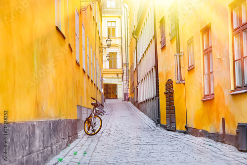 The narrow cobblestone street with a bicycle and yellow medieval houses of Gamla Stan historic old center of Stockholm at summer sunny day.