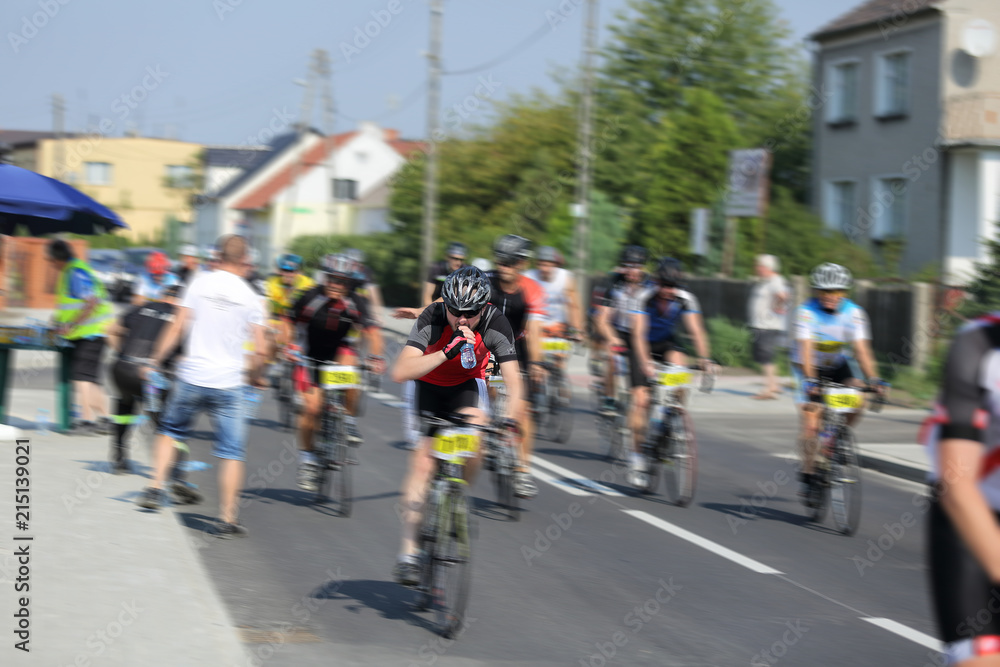 Obraz premium Rowerzyści na trasie pobierają i piją wodę w butelkach.