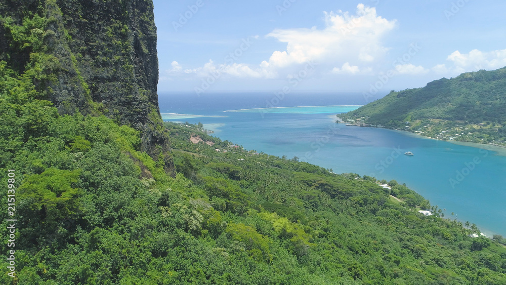 AERIAL: Flying close to a steep hill overlooking the calm bay in sunny Moorea.