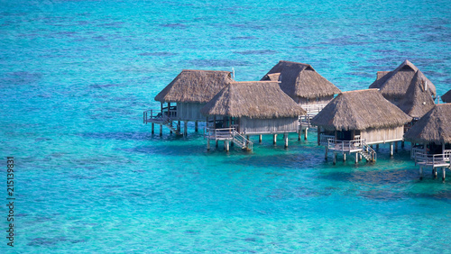Empty overwater villas sitting in the middle of the crystal clear exotic sea.