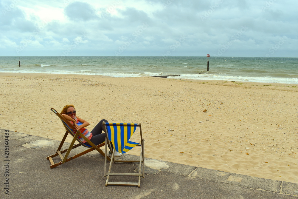 Blond girl sitting on a deck chair on the beach, Bournemouth, England Blond girl sitting on a deck chair on the beach, Bournemouth, England