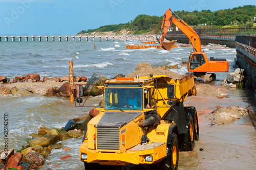 Construction of breakwaters in the sea. Construction equipment and machinery on the seashore.