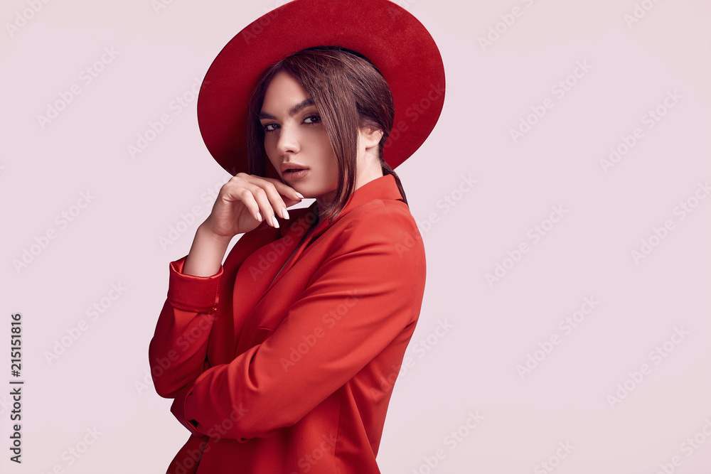 Obraz premium Elegant beautiful woman in a red fashionable suit and wide hat